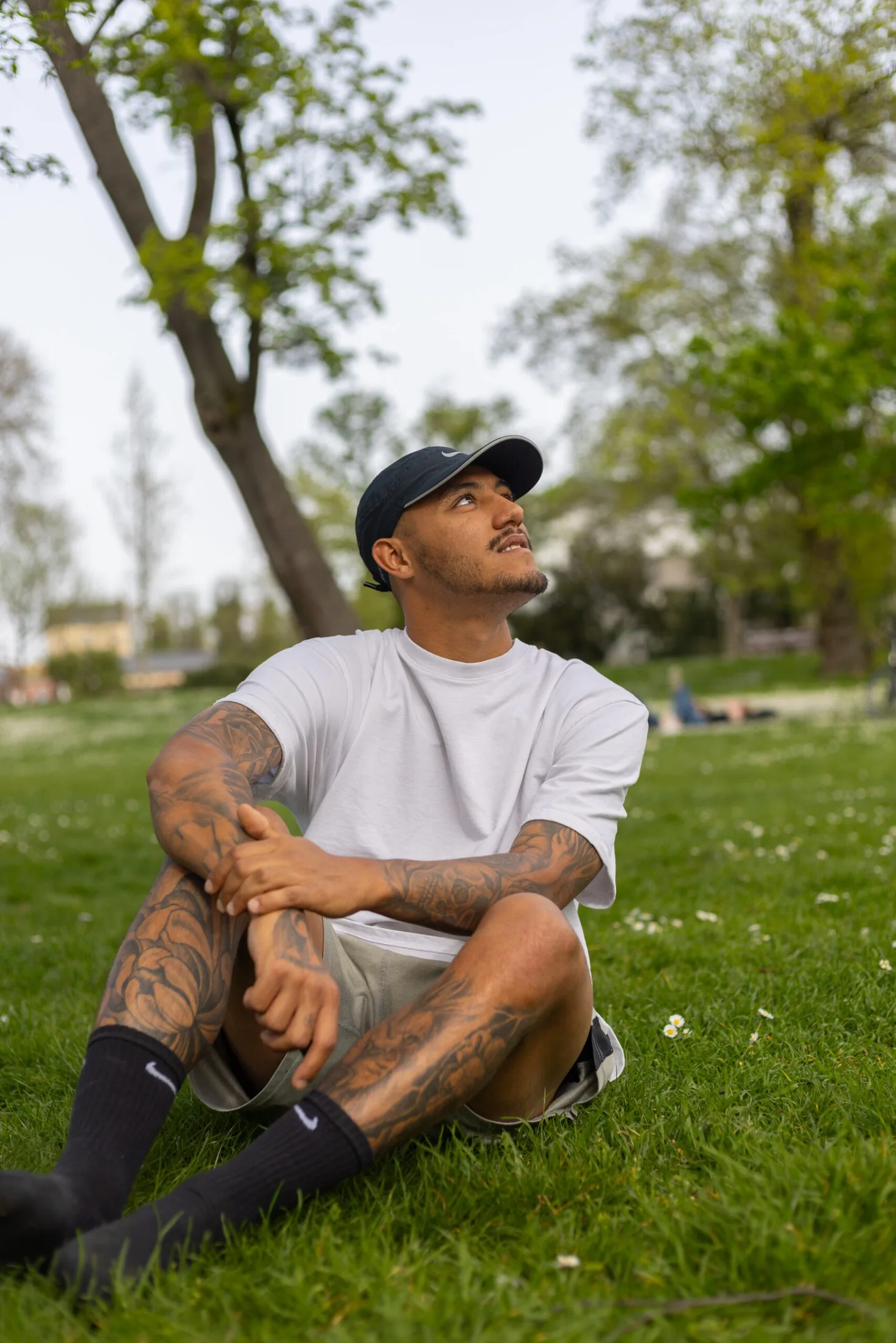 Mann mit Cap sitzt im Gras bei weichem Licht