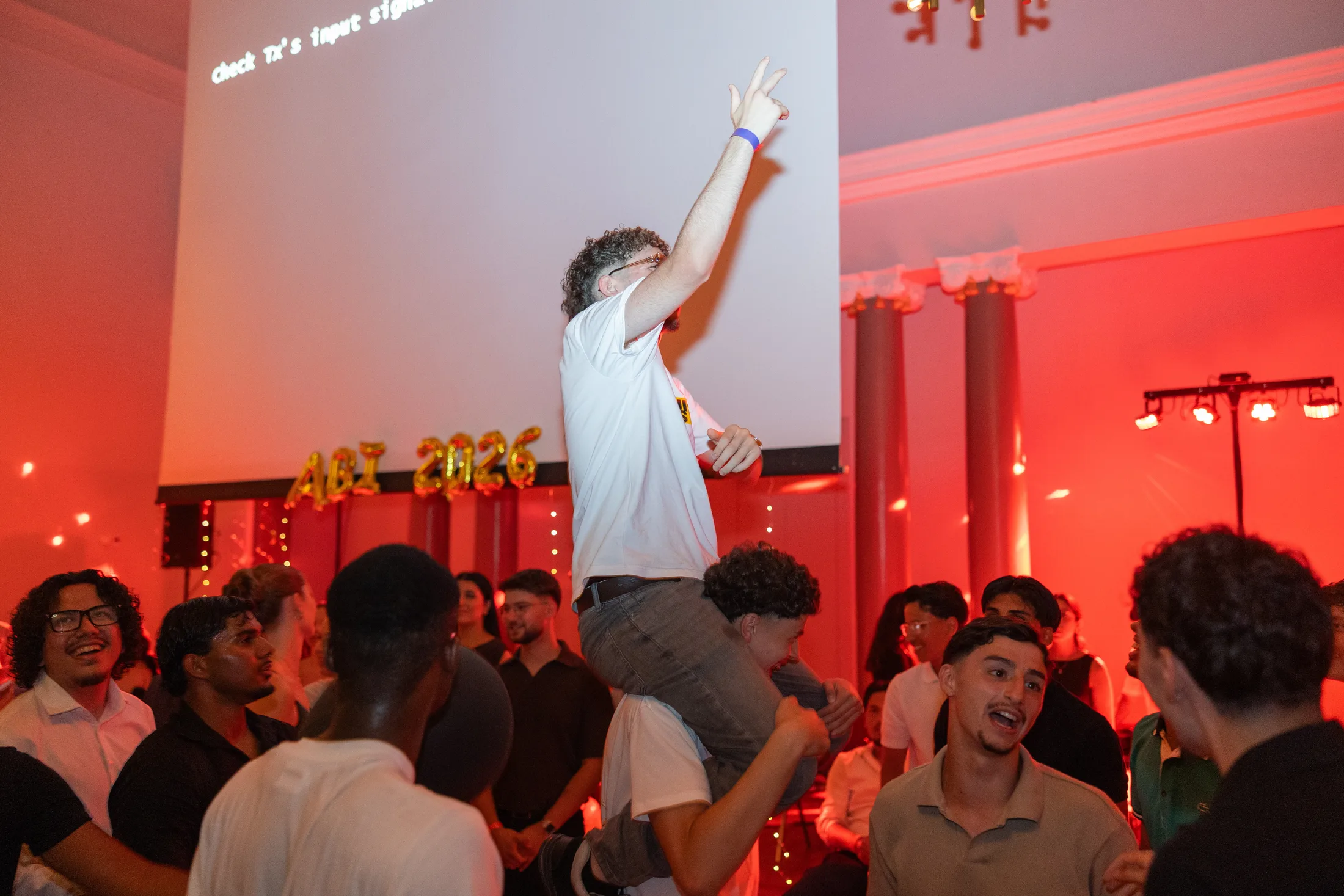 Bühne mit rotem Licht, auf der ein Mann hochgehoben wird, Eventfotografie beim Abiball