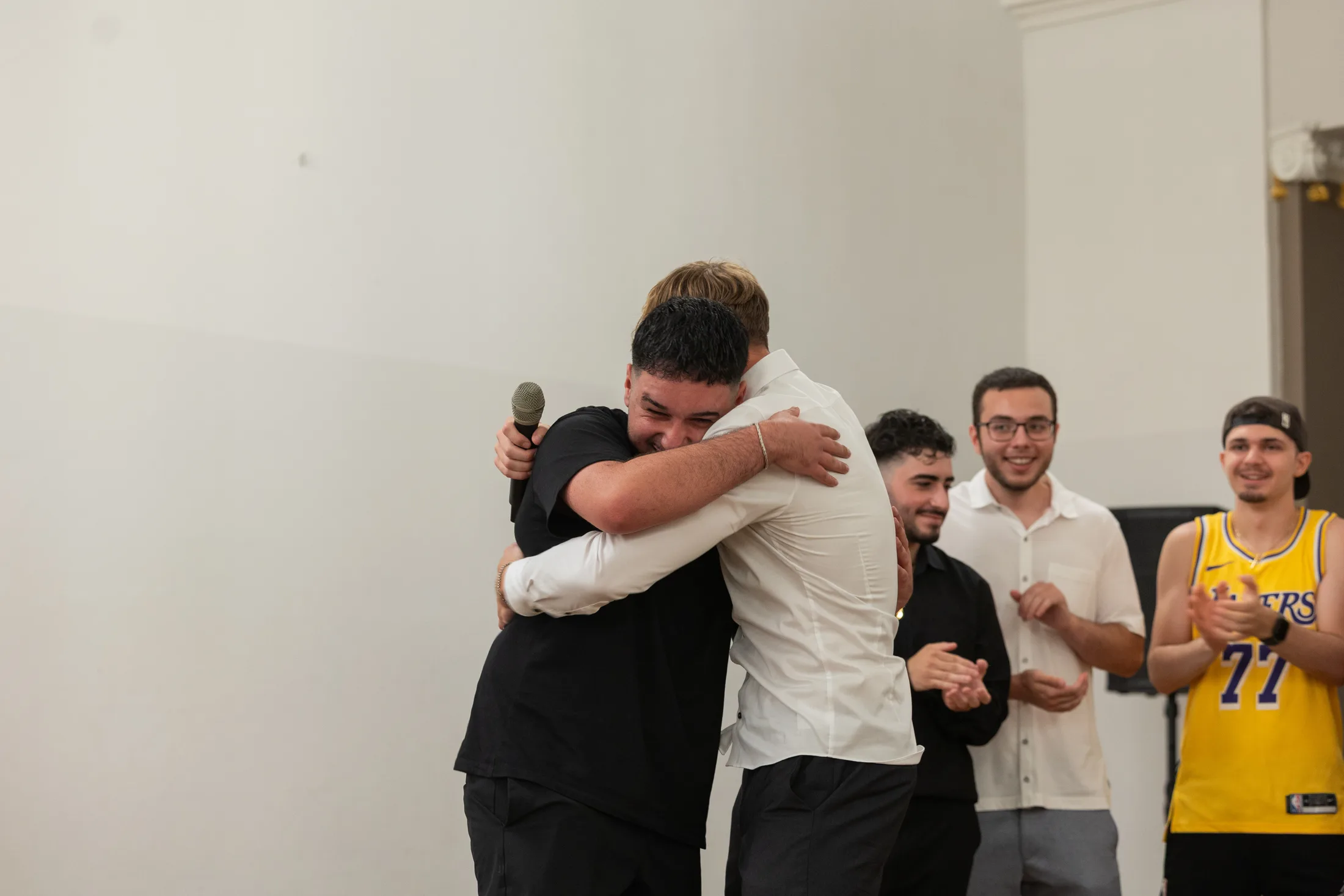 Zwei Männer umarmen sich auf der Bühne eines Abiballs