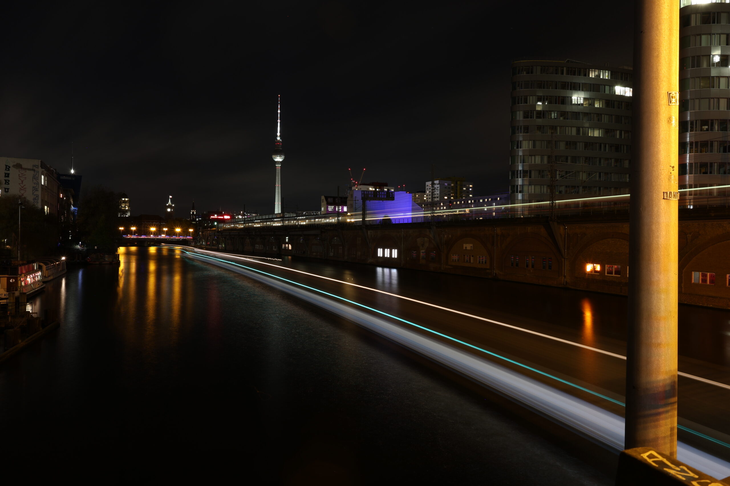 eine langzeitaufnahme der spree mit dem alexanderplatz im hintergrund