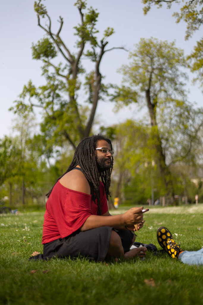 Person sitzt entspannt im Park auf dem Rasen, warmes Frühlingslicht, natürliche Portraitfotografie in Darmstadt.